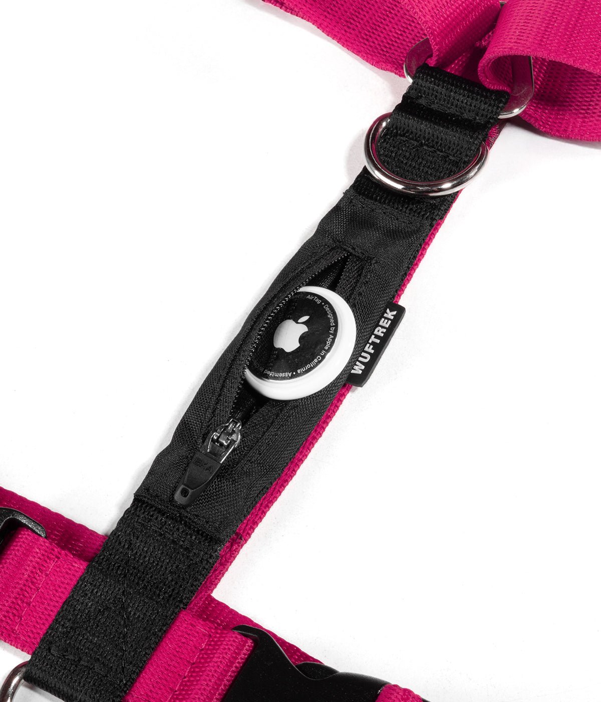 Detalle de un AirTag de Apple saliendo del bolsillo de un arnés H para perros color fucsia con negro