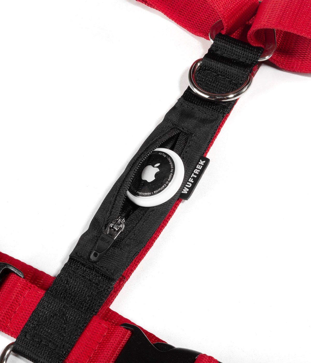 Detalle de un AirTag de Apple saliendo del bolsillo de un arnés tipo H para perros color rojo con negro