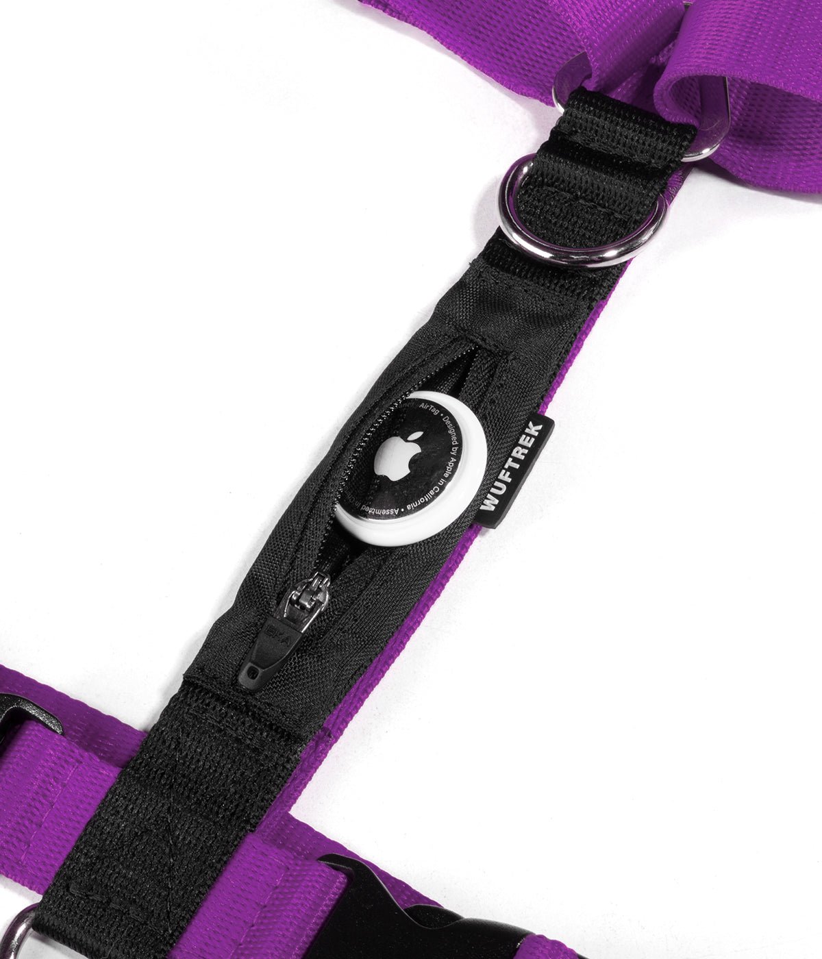 Detalle de un AirTag de Apple saliendo del bolsillo de un arnés tipo H para perros color violeta con negro