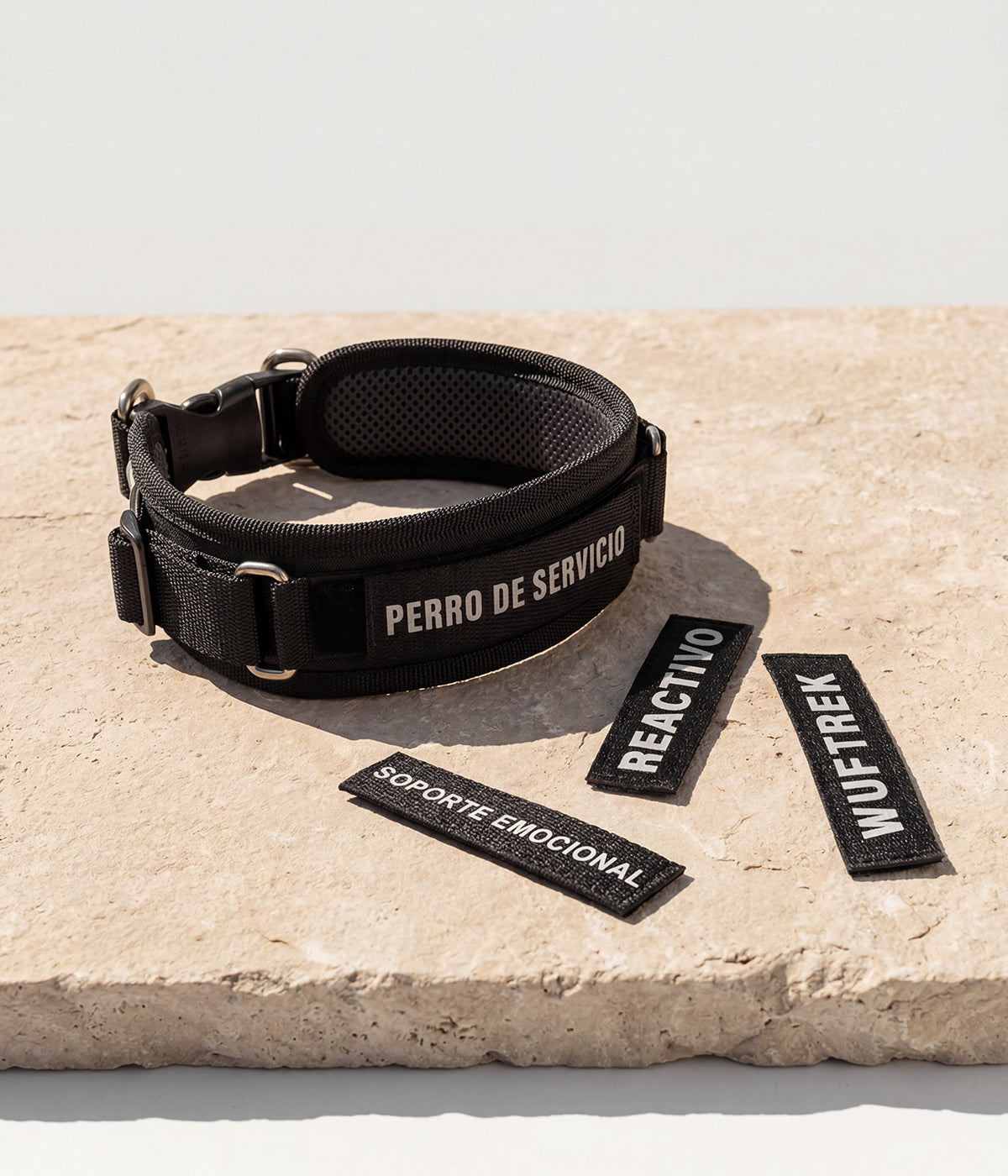 Un collar en color negro, con un parche de identificación que dice Perro de Servicio, alrededor otros parches que dicen Soporte emocional, Reactivo y WUFTREK