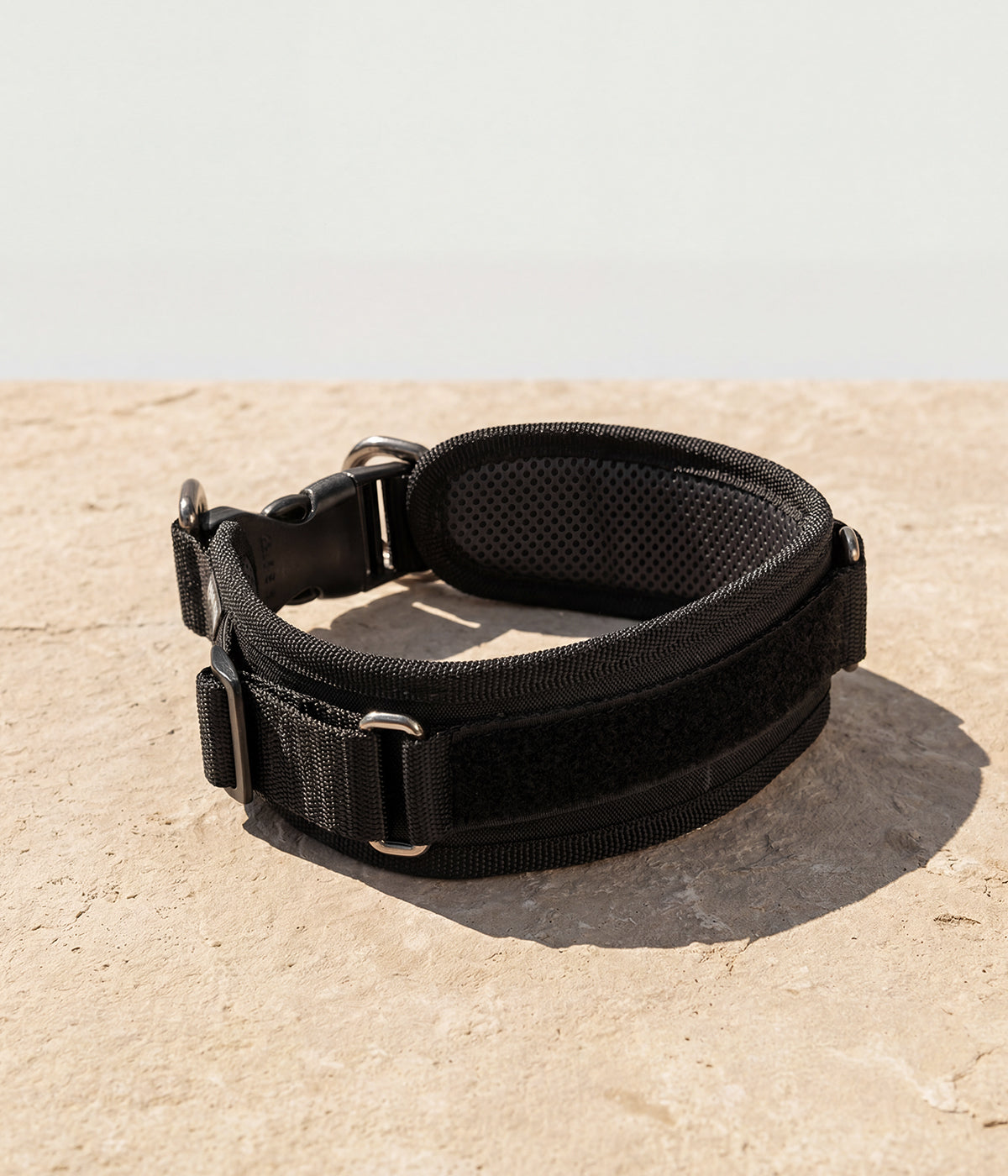 Un collar en color negro, con espacio en velcro para parche de identificación, con dos argollas adelante