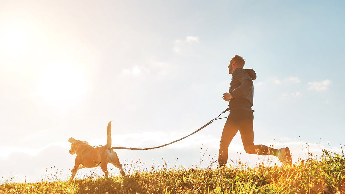 Man running outdoors alongside his dog