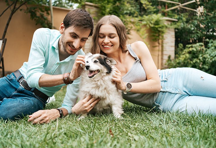 Un hombre y una mujer junto a un perro en un jardín