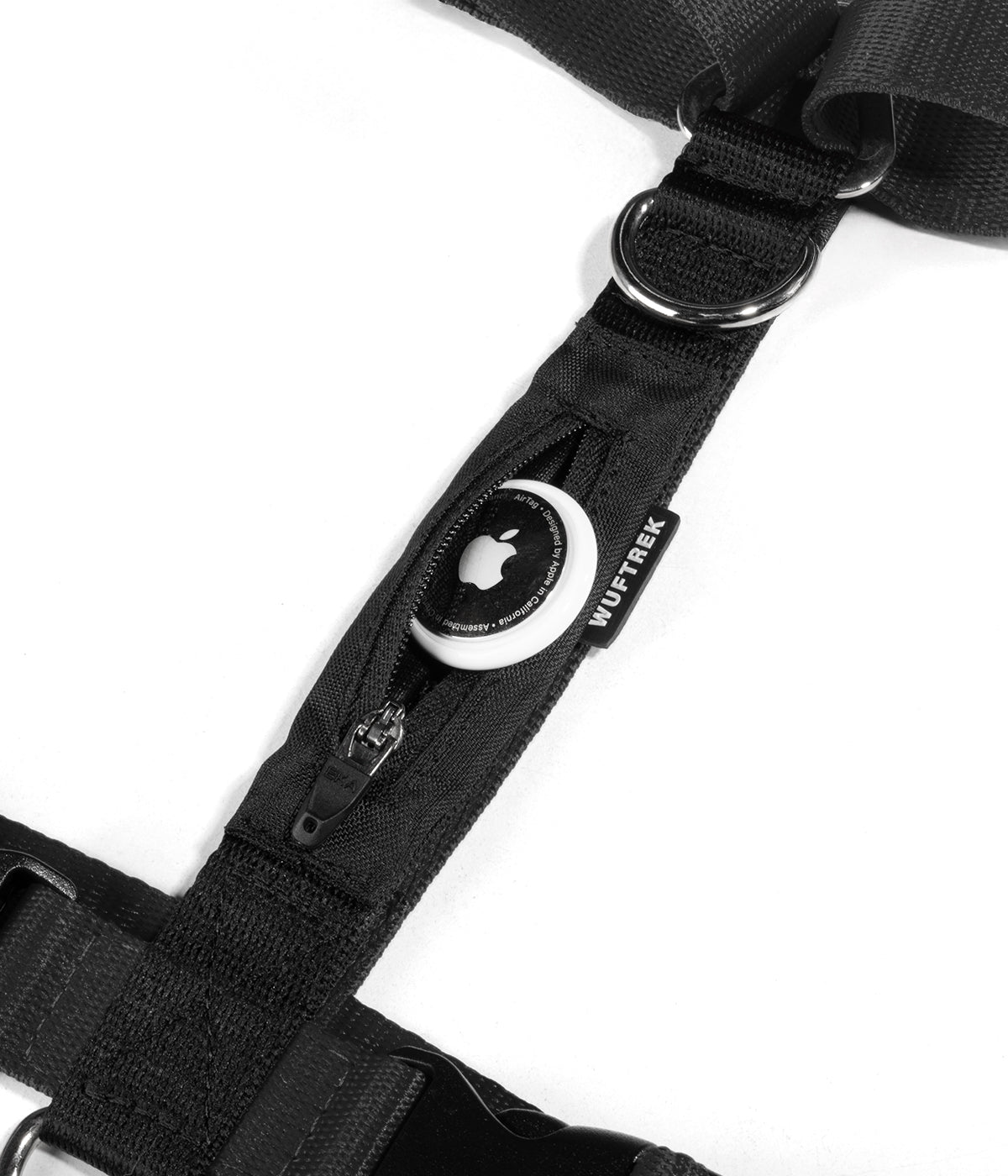 Apple AirTag partially inserted into the tracker pocket of a black TrekZero H-Series dog harness