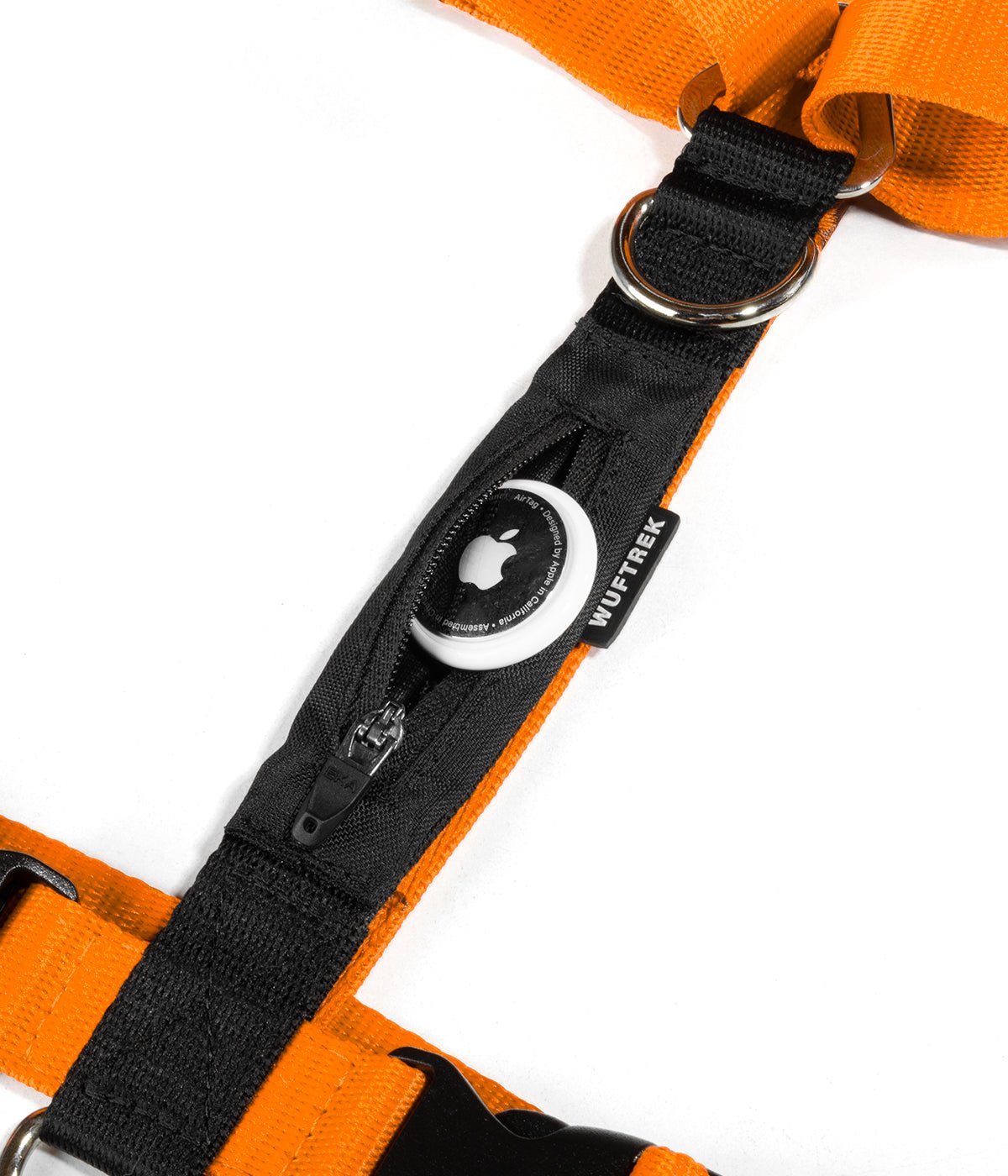 Detalle de un AirTag de Apple saliendo del bolsillo de un arnés H para perros color naranja con negro