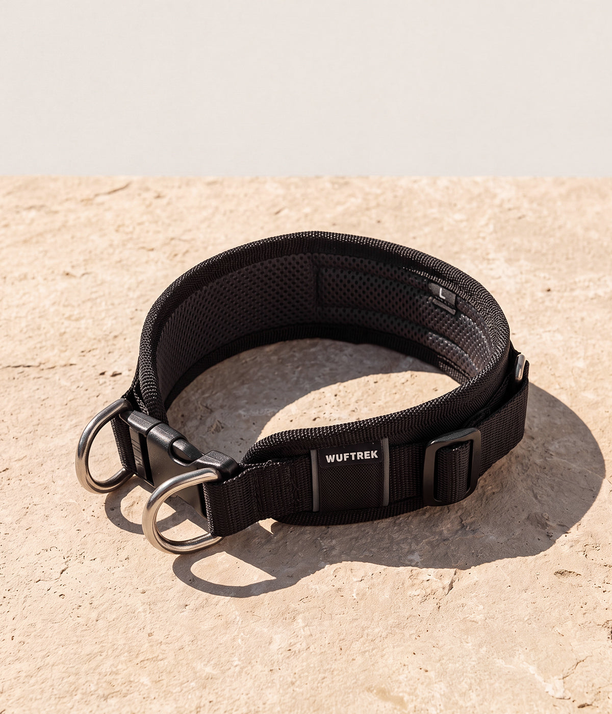 Un collar en color negro, con dos argollas de agarre adelante y hebilla de enganche