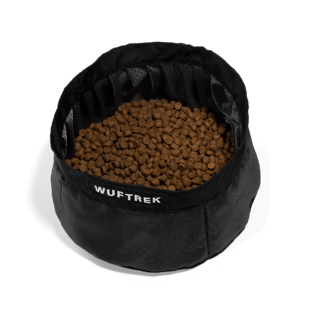 Un nomedero para perro color negro con comida para perros en su interior