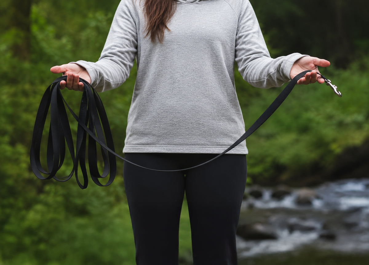 Woman holding a black long dog leash
