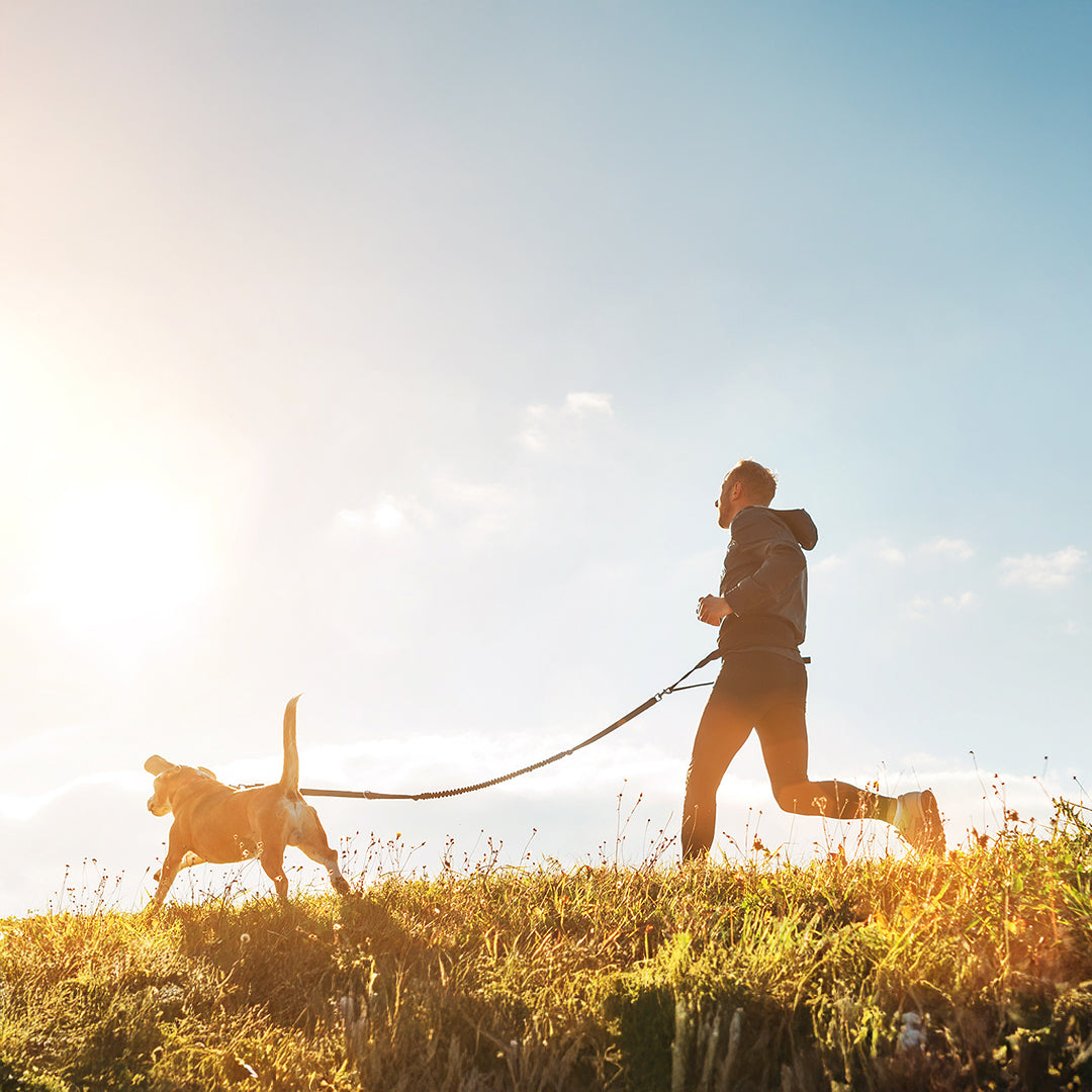 Un hombre trotando junto a su perro