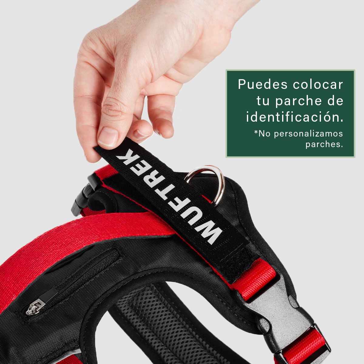 Una mano sosteniendo un parche sobre un velcro en la parte de atras de un arnés, se puede ver una argolla, una manija de control y un bolsillo en el arnes